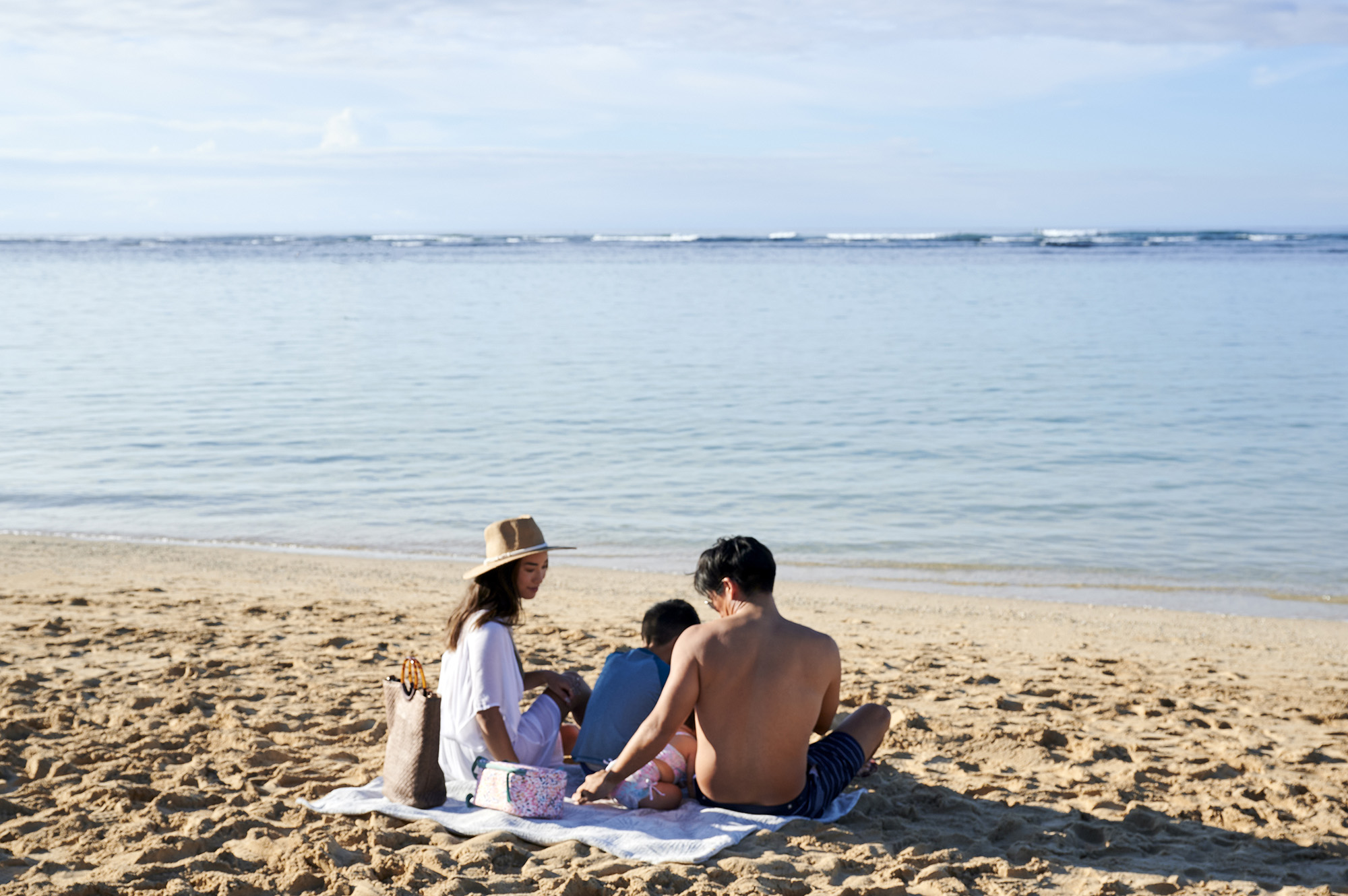 Young family sitting on beach sand