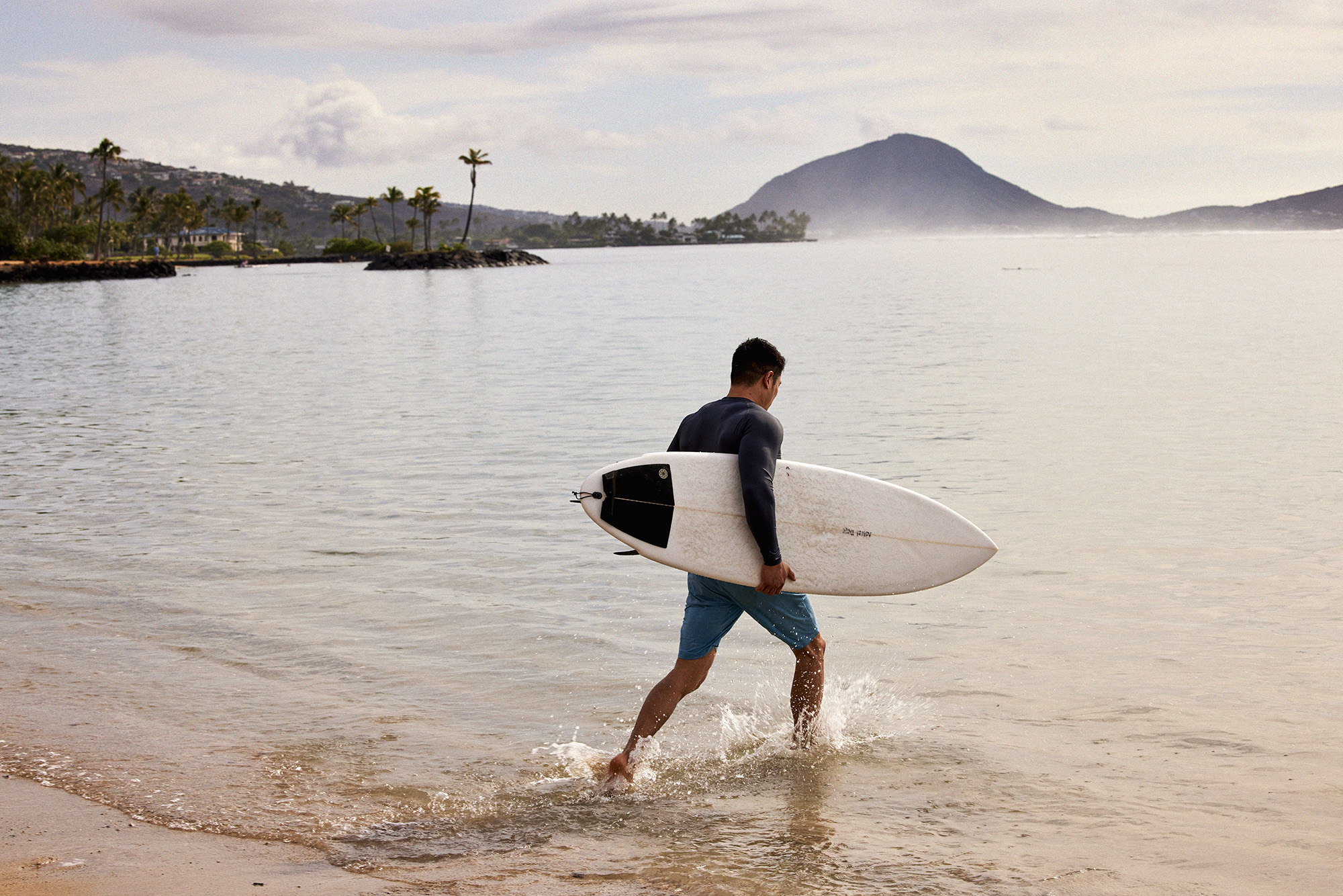 Surfer with surfboard walking into the water