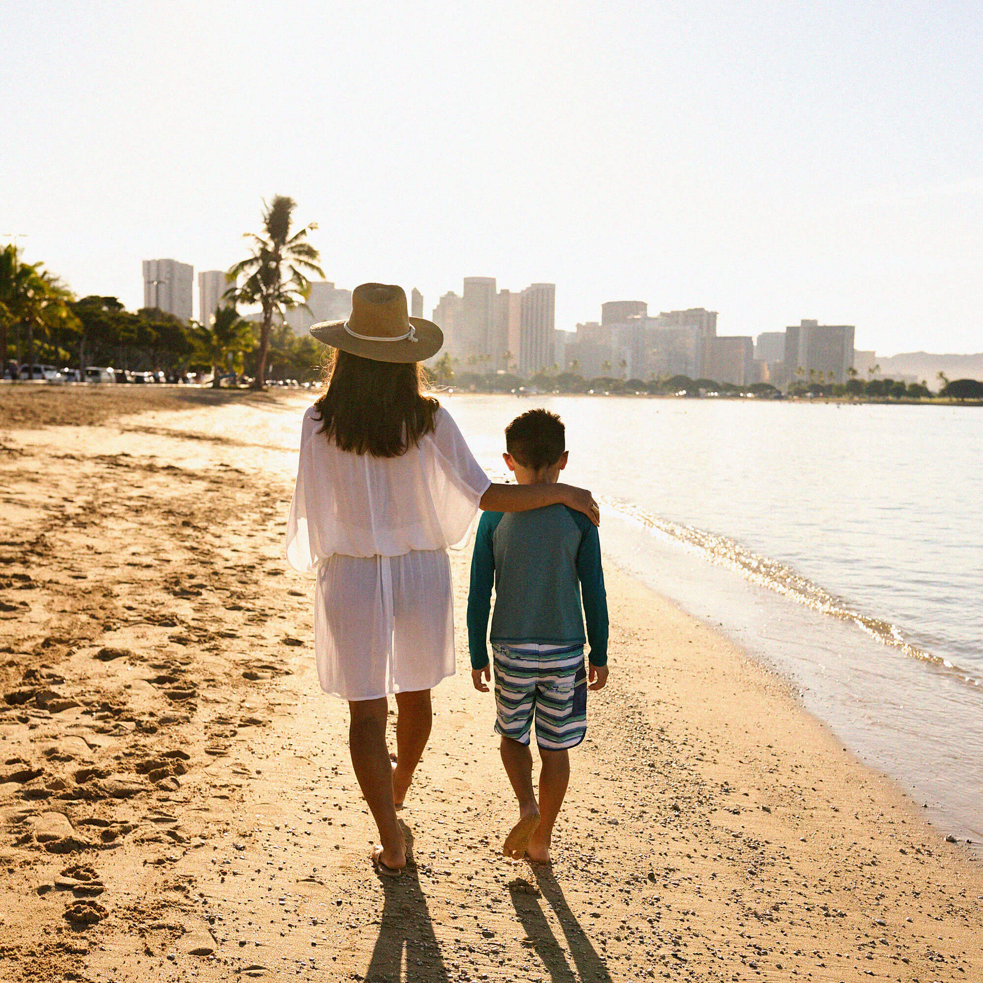 Mother and sun walking on Honolulu beach